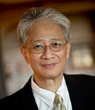 Cheow Choon, Senior Director of International Business, wearing glasses and a suit with a light tie.