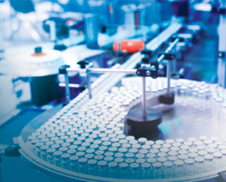 Close-up of a medical production line with equipment and vials, illustrating pharmaceutical manufacturing.