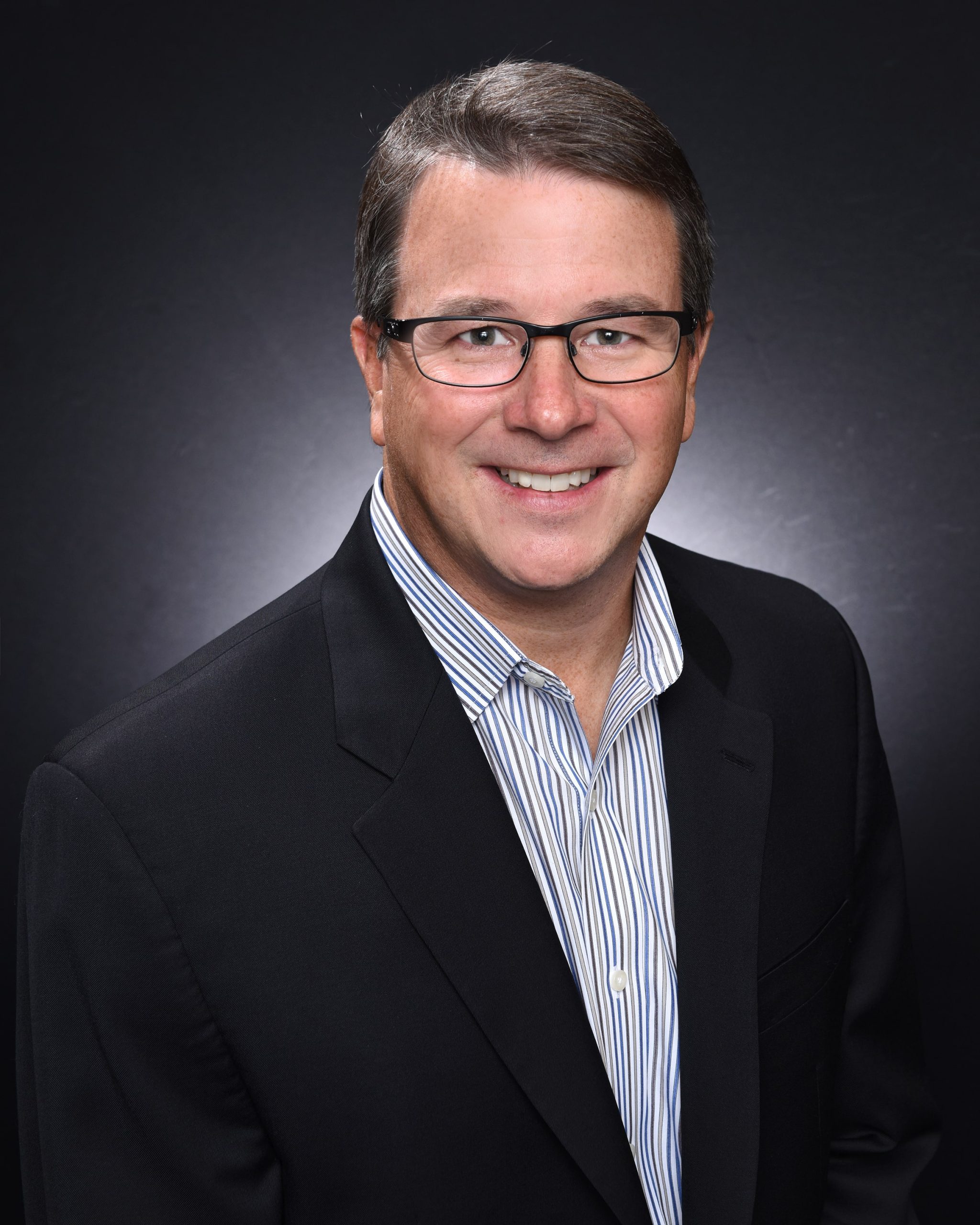 Chris Bitterman, Vice President of Sales and Marketing, smiling in a suit jacket and striped shirt