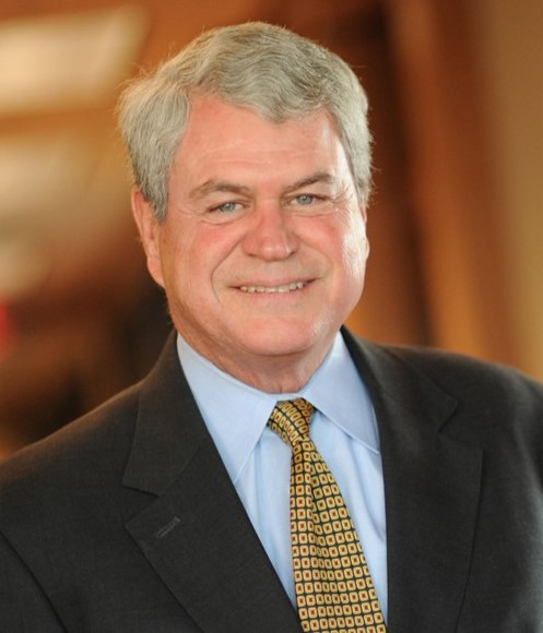 James R. Jones, Director, wearing a suit and patterned tie, smiling in a professional office setting.