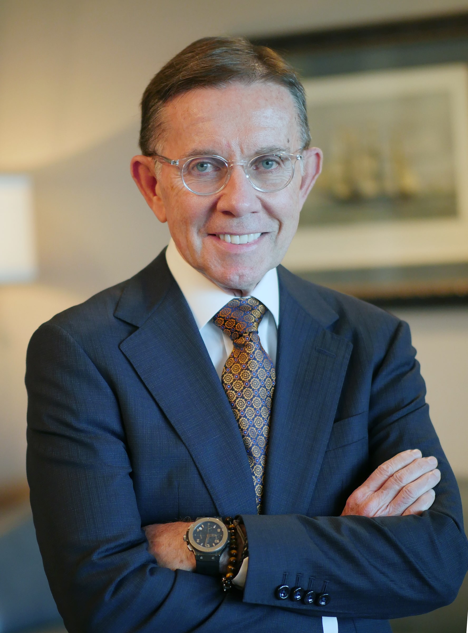 Joseph C. Galante, Director, smiling with arms crossed, wearing a suit and patterned tie in a professional setting.